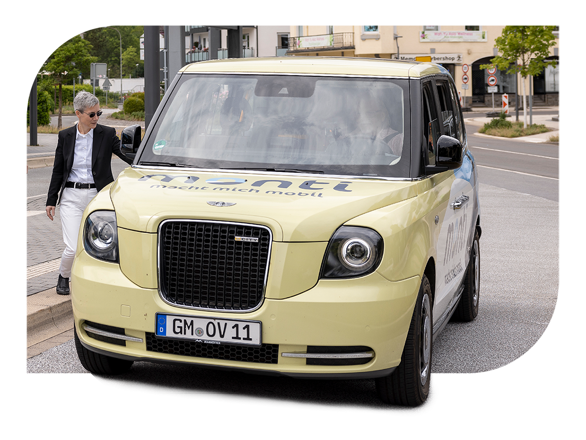 Gelbes On-Demand-Fahrzeug fährt auf einer Straße durch ein Wohngebiet.