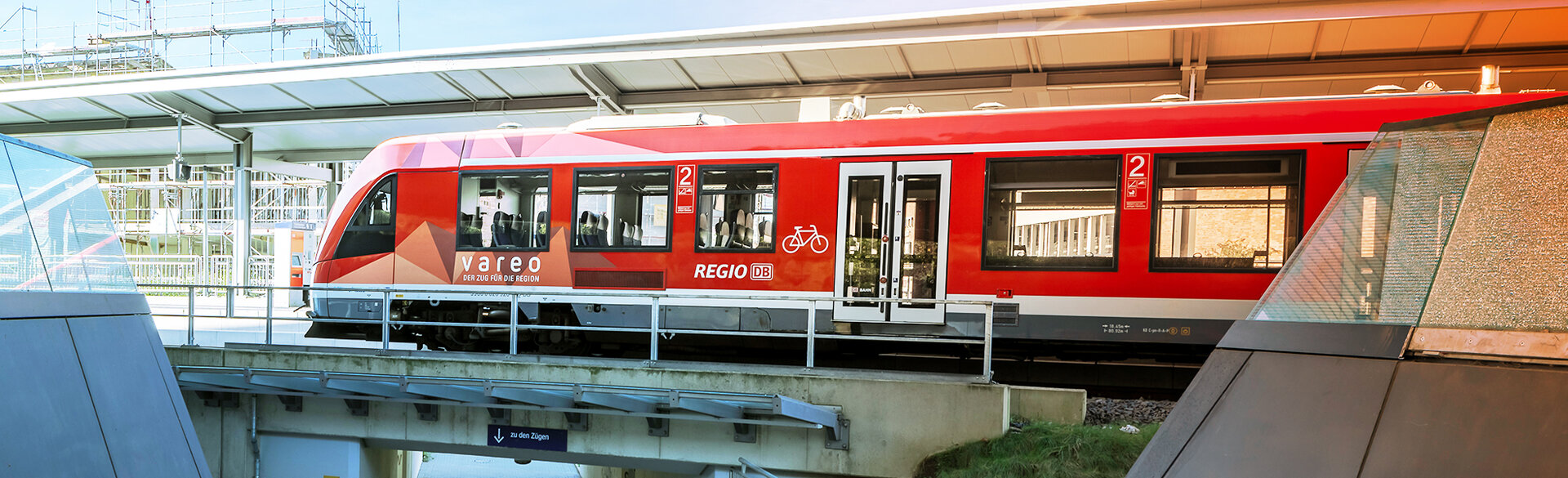 Rote Regionalbahn an einem Bahnsteig.
