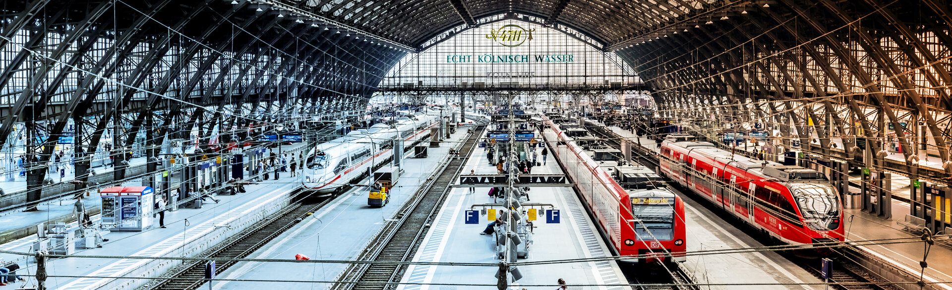Blick in eine große Bahnhofshalle mit mehreren Bahnsteigen und Zügen.