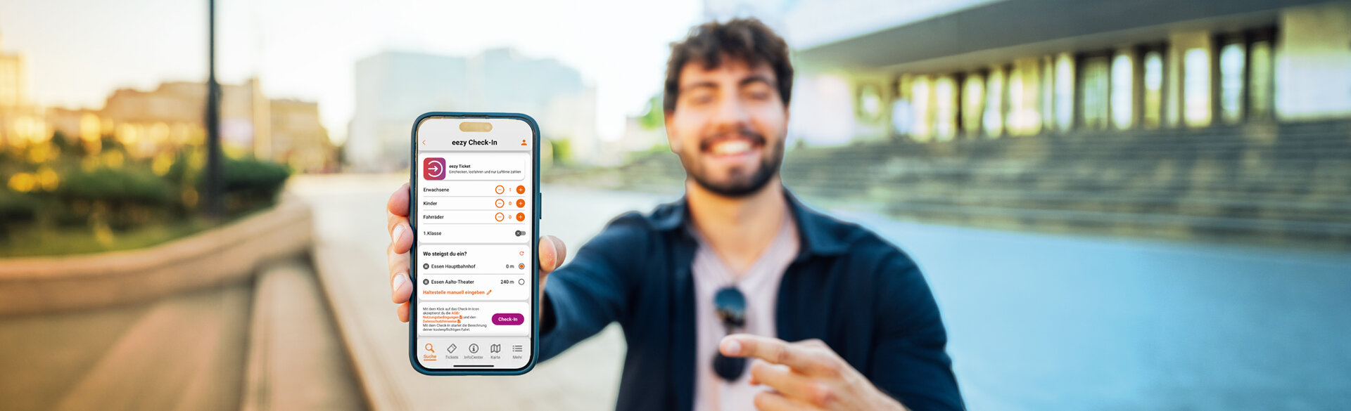 Ein Mann hält ein Smartphone mit geöffnetem eezy-Check-in in die Kamera. Auf dem Display sind das eezy-Ticket, die Auswahl der mitfahrenden Personen und der Einstieg am Essener Hauptbahnhof zu sehen.